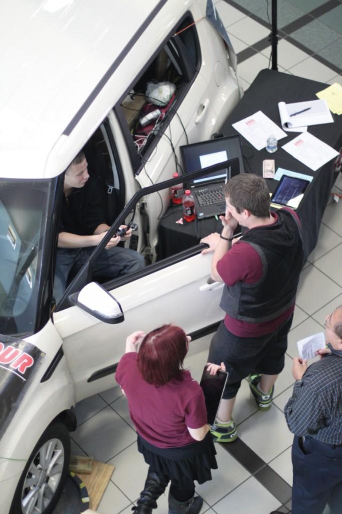 Event coordinators assist an attendee in preparing for their test drive in the drunk driving simulator.