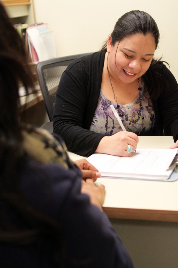 Linda Reyna helps a student fill out counseling paperwork in her office.