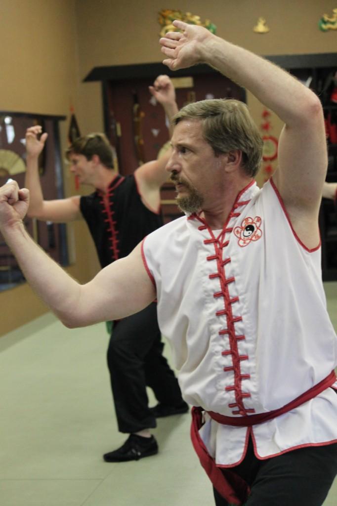 Student Joel Jenkinson watches in a mirror as instructor Jared Hall (background) guides the class through a series of movements.