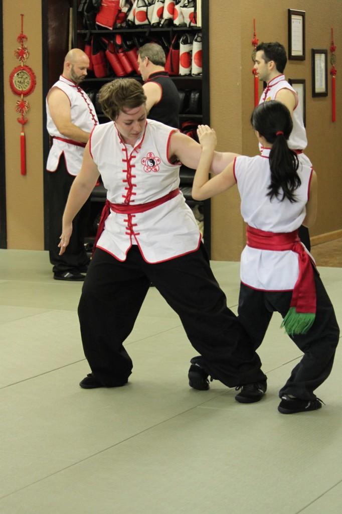 Photos by Brigitte Zumaya | From left to right: Student E. Jean Meeker practices her moves on an opponent; Sifu George Giatrakis demonstrates a Kung Fu technique; student Joel Jenkinson watches in a mirror as instructor Jared Hall (background) guides the class through a series of movements.