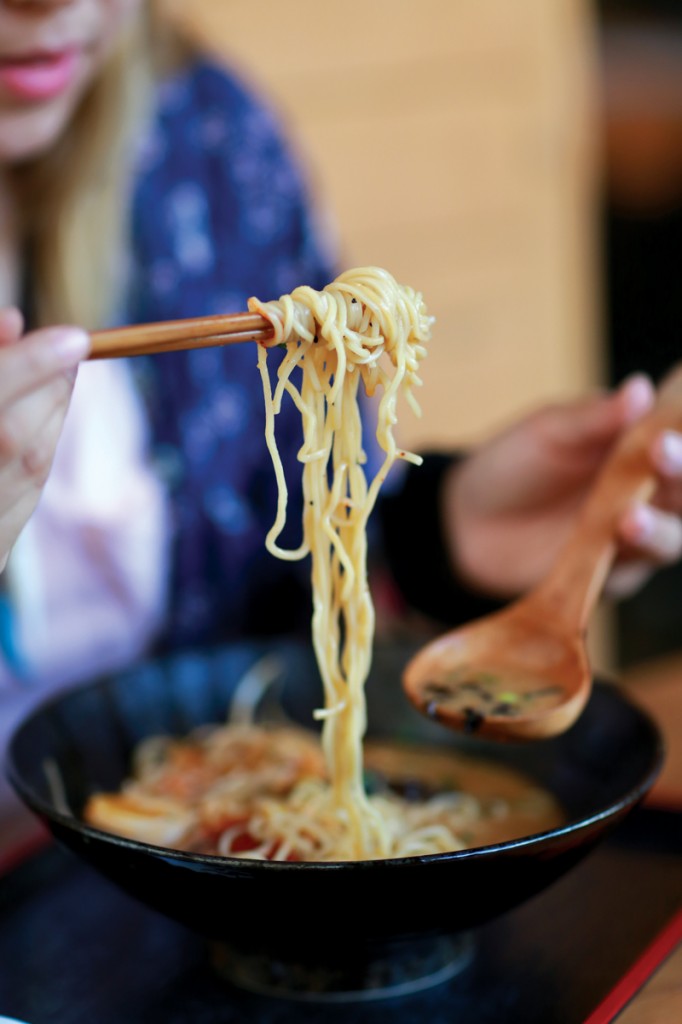 Photos by Adriana Salazar |A heap of long wheat noodles is plucked out of a bowl of spicy miso ramen with chopsticks.