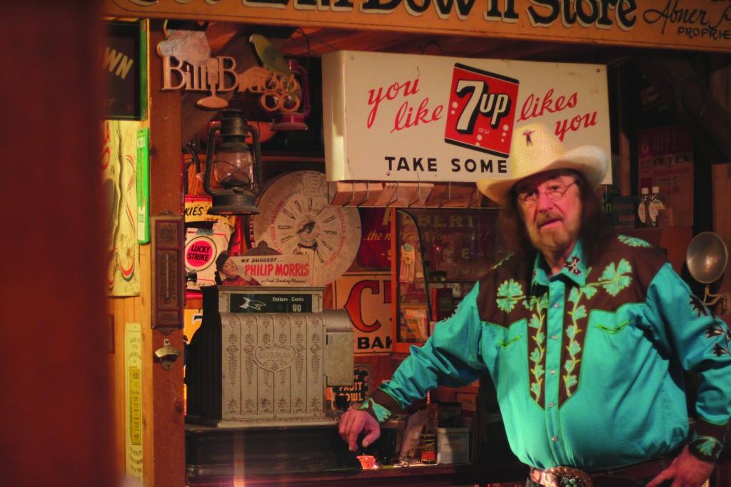 Photo by Erin Alexis Goldman | Bill Bragg stands in front of one of two 1940s general store counters in his Richardson, TX home. The avid collector also has a fully functional amusement park train ride, which meanders its way through the house giving riders a view of his celebrity wardrobe exhibit and a collection of 5,000 die cast miniature model cars.