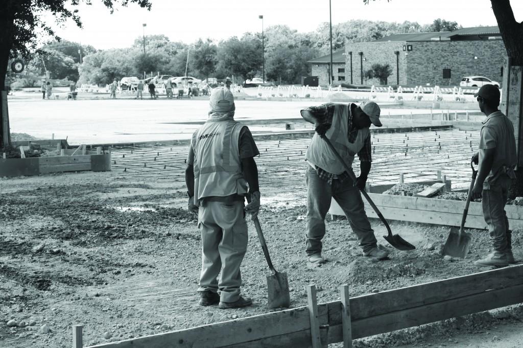 Photo by Nicholas Bostick | Courier Construction workers shoveling gravel in parking lot P5 in preperation for concrete to be poured.
