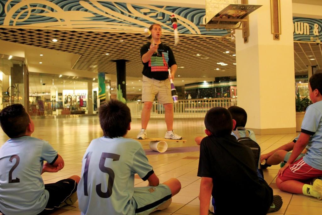 Photo by Brigitte Zumaya | Brookhaven College chemistry professor Alan Blakely balances on a rola bola while juggling clubs for excited children in Valley View Center.