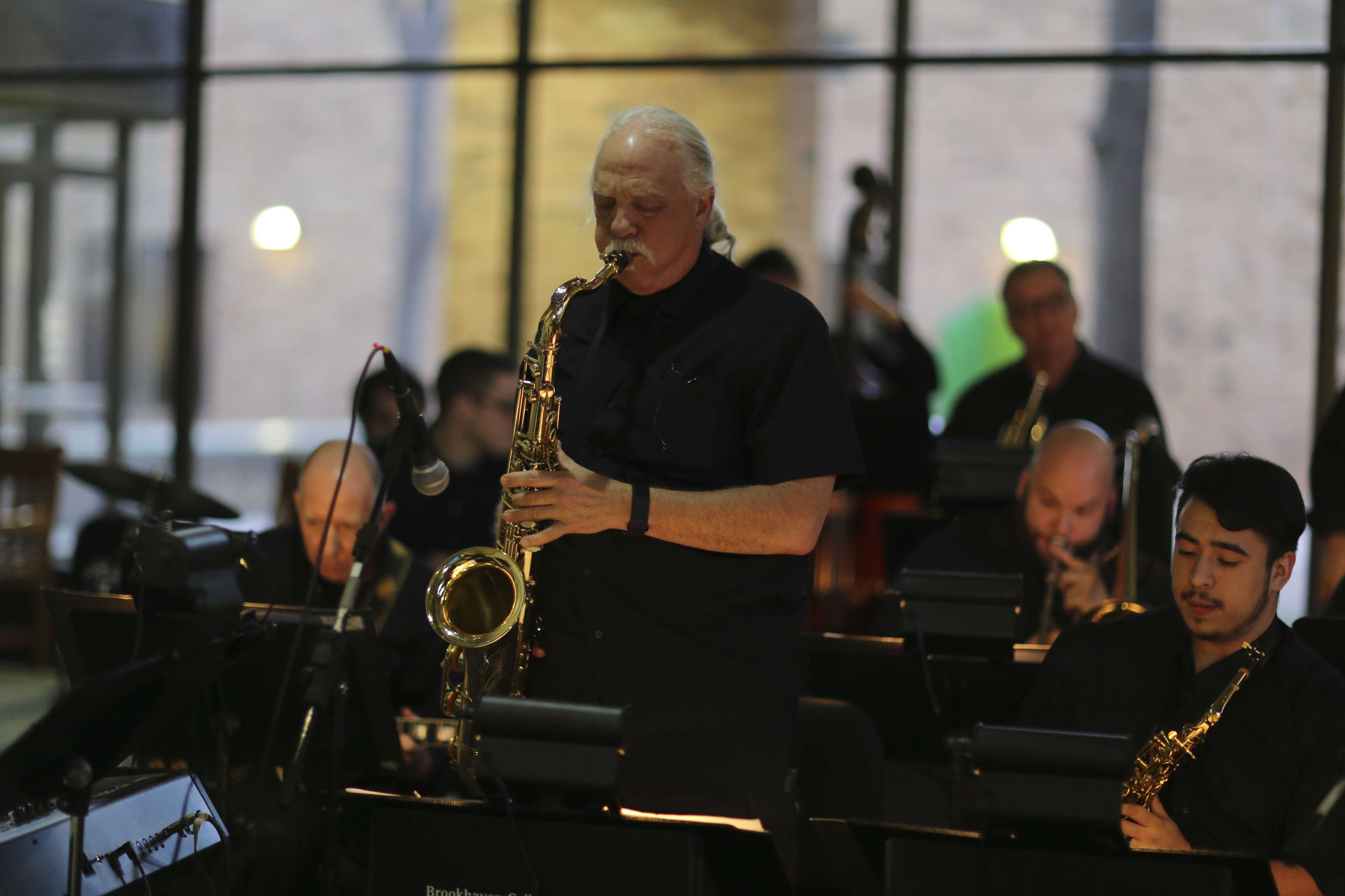 Brookhaven Big Band member Dan Ebie rocks out on his saxophone as guests mill about the Performance Hall lobby.