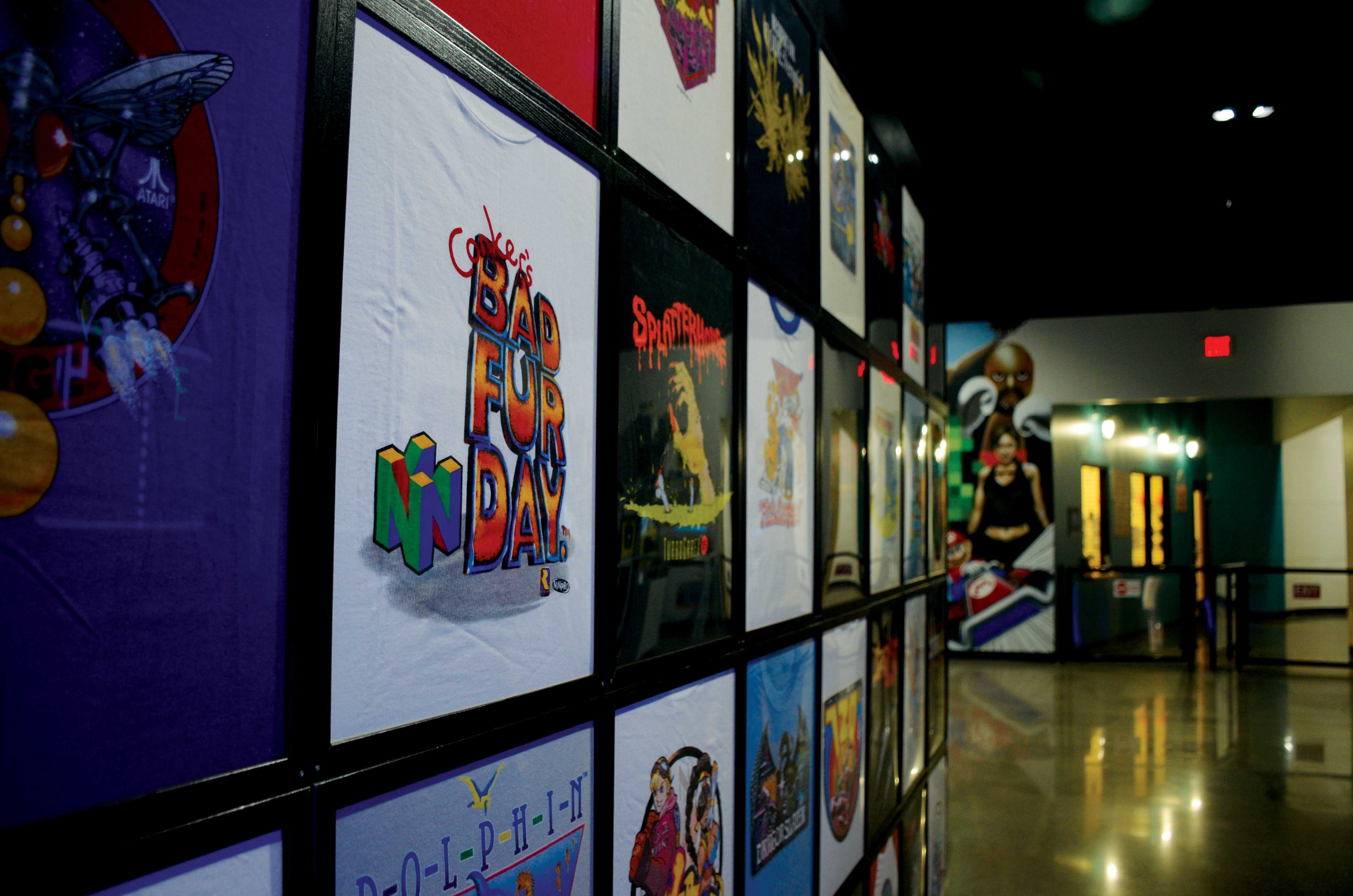 A grid of vintage video game T-shirts hang on a wall in the museum.