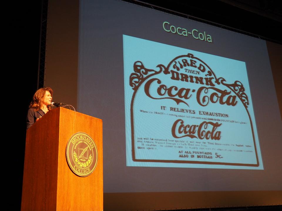 Photo by Jubenal Aguilar Monica Rankin, director of the University of Texas at Dallas Center for Latin American Initiatives, talks about the origins of Coca-Cola. The beverage, originally made from coca leaves and African kola nuts, was marketed as alleviating many of the symptoms patented medicines already were, including exhaustion.