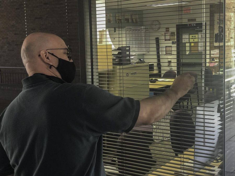 Photo of instructor scraping sticker off window on campus