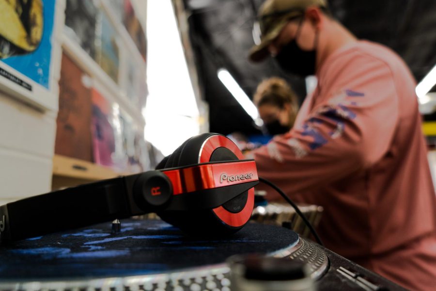 Photo of turntable with someone next to it looking through records