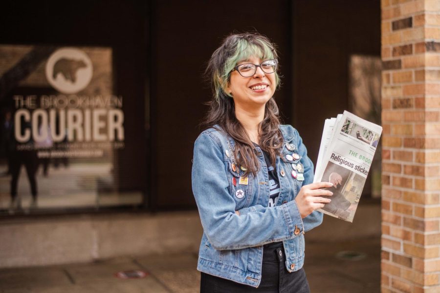 Stephanie Salas-Vega, a former editor of The Courier, in front of her old stomping grounds with most recent issue from The Courier.