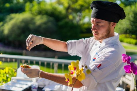 Dallas College student Christopher Ourfalian applies sesame seeds to a single yakisoba noodle salad with Asian dressing and smoked duck breast on top.