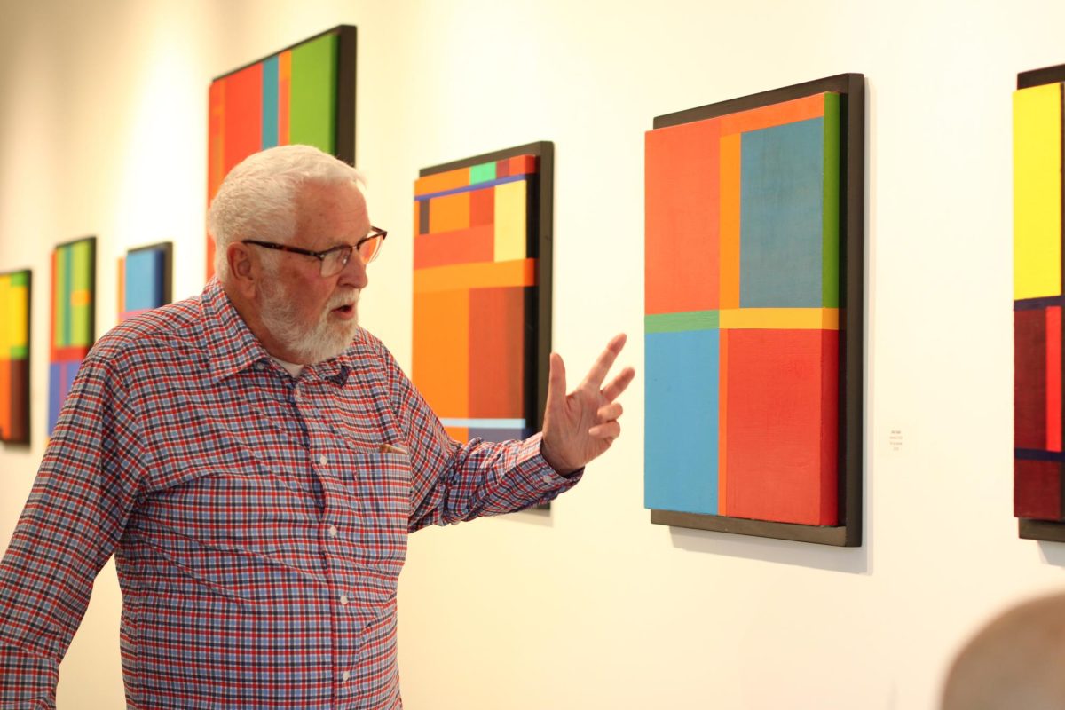 Don Taylor gestures toward his artwork on the wall.