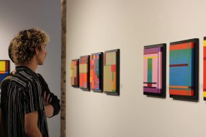 Students watching artwork on a wall.