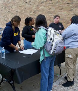 Staff handing paperworks to students.