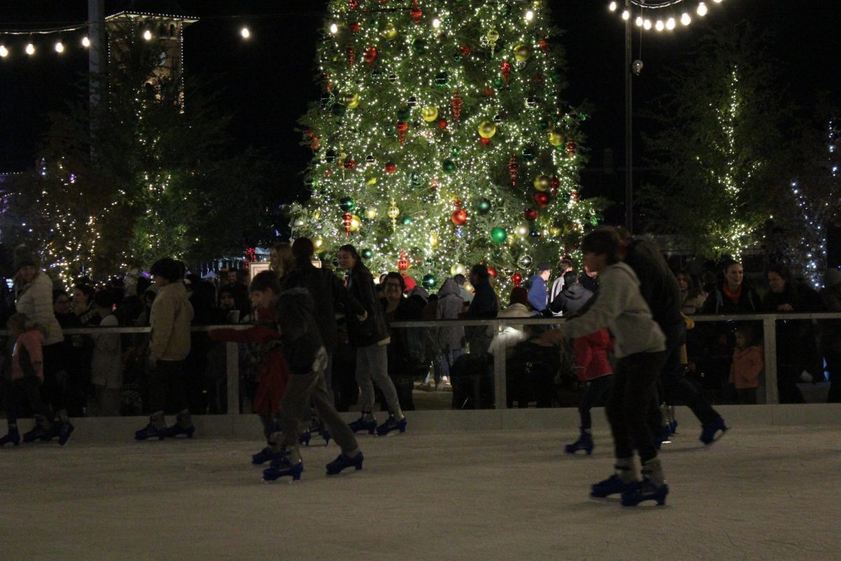 People skating by a Christmas tree.