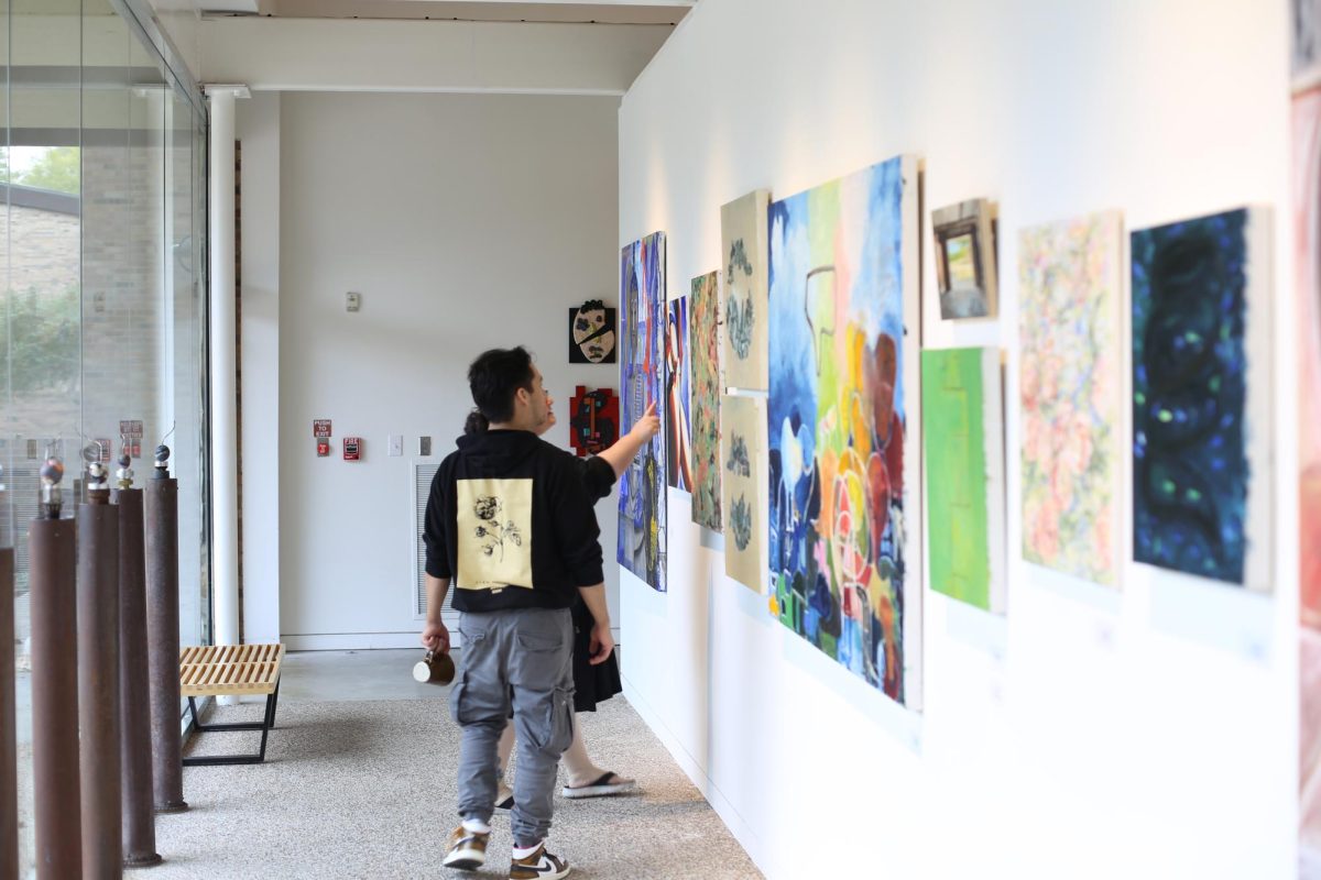 People looking at arts posted on the wall.