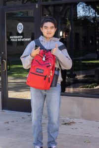 Boy carrying his backpack with thumbs up.