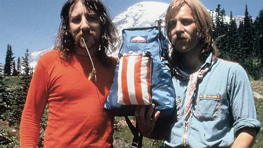 Two men holding a backpack.