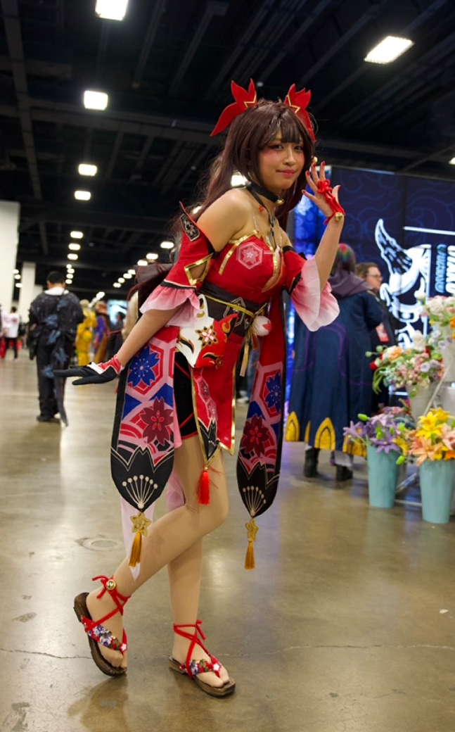 A girl in costume with her hand on her face and one leg slightly up.