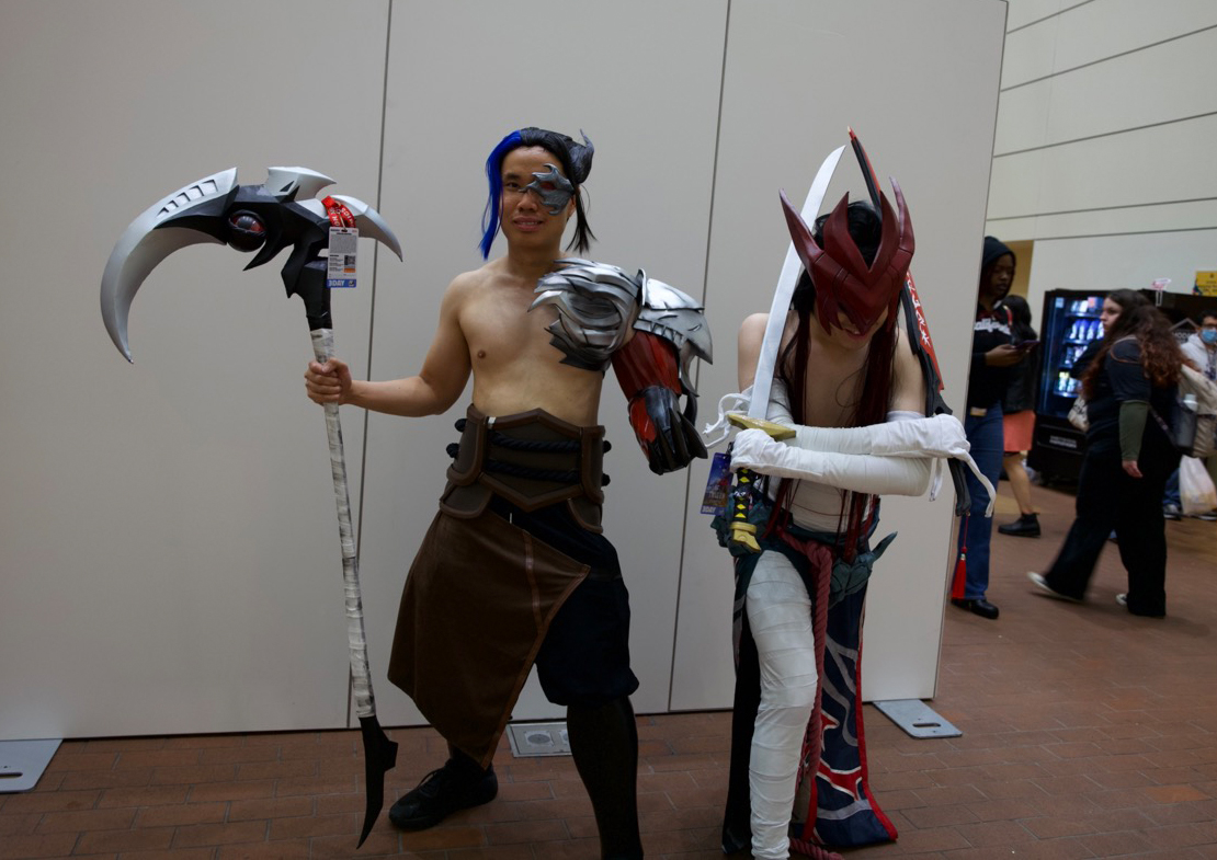 Two men in costume holding props and posing for the camera.