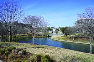 A river in a park by the buildings.