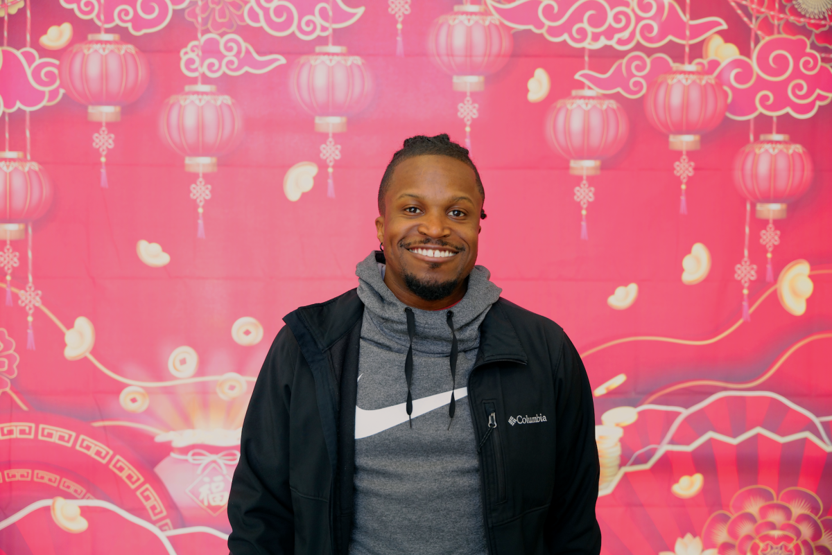 A man standing in-front of a red background.