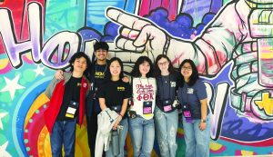 A group of people posing in front of a wall.
