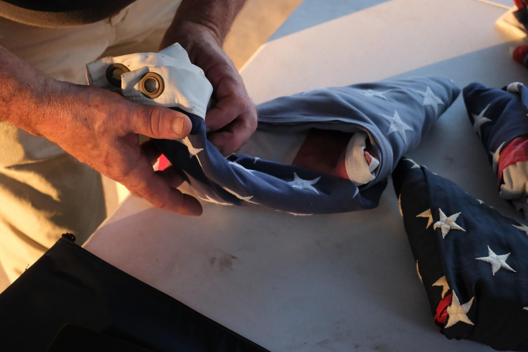 A man folds the American flag into a triangle. 
