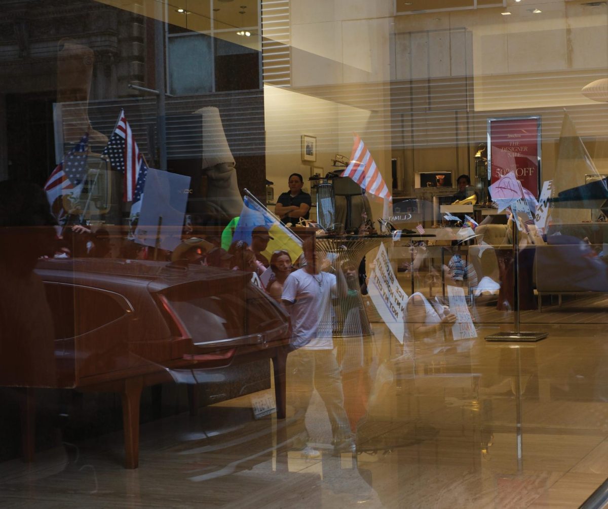 A worker looks out as protestors pass by his place of work. 
