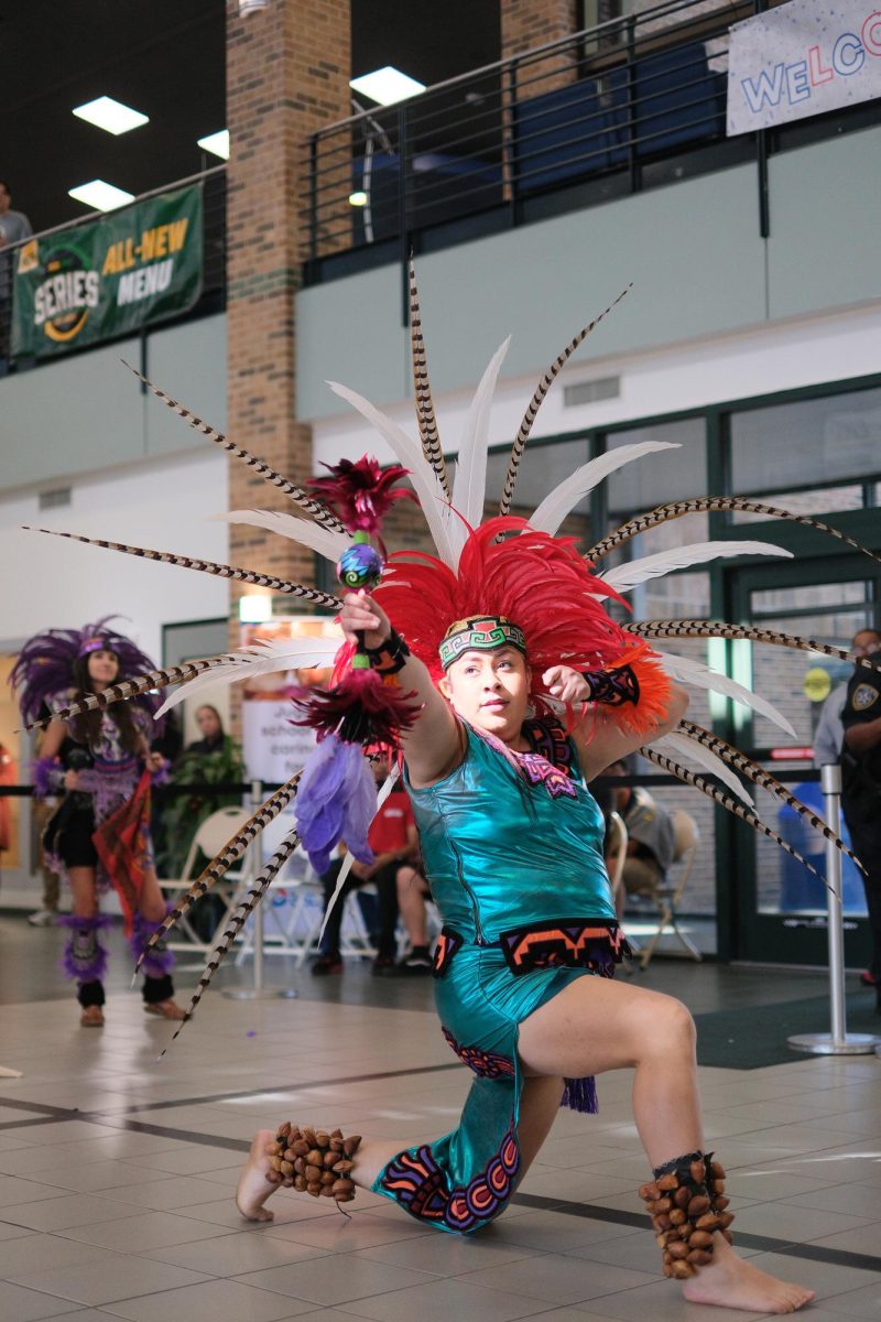 Indigenous dancers perform in the S Building to a gathered crowd. 