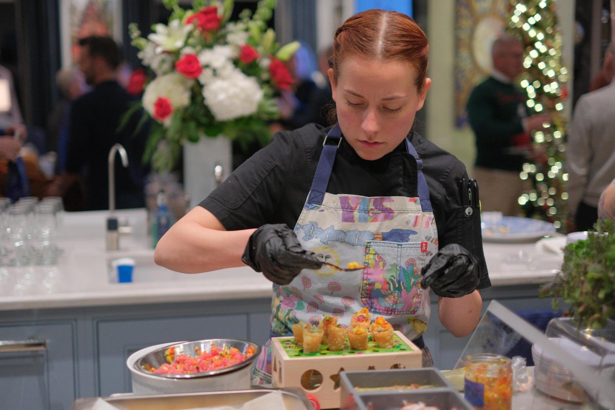 Chef Andrea Saldana plates up her dish on one of her son’s baby toys at a fundraising dinner for the Resource Center.